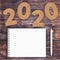 Cardstock Numbers 2020 Happy New Year Sign near White Spiral Paper Cover Notebook with Pen over table. 3d Rendering