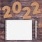 Cardstock Numbers 2022 Happy New Year Sign near White Spiral Paper Cover Notebook with Pen over table. 3d Rendering