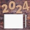 Cardstock Numbers 2024 Happy New Year Sign near White Spiral Paper Cover Notebook with Pen over table. 3d Rendering