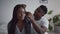 Care of loving spouses. Young caring african american husband combing hair of black wife, sitting together in bedroom