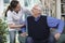 Care Worker Helping Senior Man To Get Up Out Of Chair