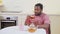 carefree african man resting at kitchen of apartment in holiday, drinking tea and surfing internet