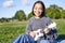 Carefree asian girl singing and playing ukulele in park, sitting on grass, musician relaxing on her free time outdoors