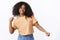 Carefree attractive happy young african-american curly-haired girl wearing spring orange t-shirt dancing waving hands