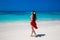 Carefree beautiful woman enjoying on the exotic sea. Happy brunette girl in red dress relax on tropical beach island. Summer