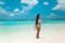 Carefree bikini Woman on tropical beach. Pretty slim girl with coctail enjoying on exotic island in turquoise ocean. Brunette