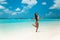 Carefree bikini Woman on tropical beach. Pretty slim girl with coctail enjoying on exotic island in turquoise ocean. Brunette