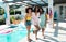 Carefree biracial millennial female friends laughing while enjoying by pool during weekend in summer