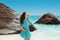 Carefree brunette woman in blue dress enjoying life near seashore in tropical beach with rocks. Enjoyment. Lifestyle. Freedom.