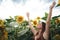 Carefree Caucasian young woman smiling with arms raised in sunflower field during spring season