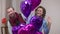 Carefree cheerful adult loving couple waving looking at camera with heart shape balloons at front. Middle shot of