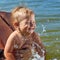 Carefree child bathes in the water in her motherâ€™s arms