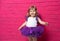 Carefree cute little girl in tutu skirt laughing out loud giggling on pink background