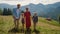 Carefree family stroll mountain slope summer holiday. Couple walking with kids.