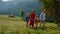 Carefree family walk together on green slope. Parents enjoying nature with kids.