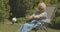 Carefree female retiree sitting in garden chair and applying hand moisturizer. Portrait of happy relaxed Caucasian lady