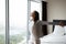 Carefree female tourist admiring sight from panoramic window of hotel