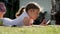 Carefree girl is playing on the tablet. Lies on the grass near the house, the sun illuminates her hair. Close up