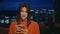 Carefree girl strolling night city holding smartphone closeup. Lady using mobile