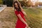 Carefree girl in stylish red dress dancing in sunny day. Enthusiastic brunette young woman in summer