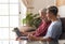 Carefree grandfather and grandson sitting together on the sofa at home looking at the same laptop smiling - sharing the same