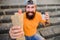 Carefree hipster eat junk food while sit on stairs. Hungry man snack. Guy eating hot dog. Man bearded bite tasty sausage