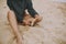 Carefree hipster girl holding herb and sitting on beach, cropped view on tanned legs. Stylish boho woman in modern swimsuit and