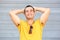 Carefree man smiling with hands behind head against gray wall