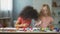 Carefree multiracial female kids sitting at the table and painting, art hobby