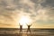 Carefree multiracial senior couple jumping with arms raised at beach against sky during sunset