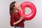 Carefree positive girl biting inflatable big donut, pretending to eat rubber ring, having fun on summer vacation