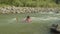 Carefree pretty african american woman in bikini floating down on inflatable mattress on mountain river