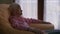 Carefree relaxed old woman thinking looking at camera and looking away sitting indoors. Side view senior Caucasian