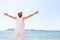 Carefree senior woman standing at beach against clear sky. Rear view of female with arms outstretched is in casuals