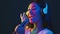 Carefree Singer. Young asian lady in wireless headphones singing favorite song at microphone in bright neon lights