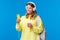 Carefree smiling blond woman in yellow hoodie listening music in headphones, picking song from playlist as drinking