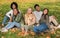 Carefree teen friends sitting on the ground at public park