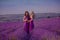 Carefree two beautiful women enjoying sunset in lavender field. Harmony. Attractive blond and brunette with long curly hair style