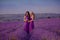 Carefree two beautiful women enjoying sunset in lavender field. Harmony. Attractive blond and brunette with long curly hair style