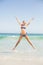 Carefree woman in bikini jumping on the beach