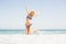 Carefree woman in bikini jumping on the beach