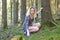 Carefree woman crouching on a forest floor in tattered dress