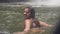 Carefree woman splashing water while bathing in mountain lake on water flow background. Happy woman enjoying water in