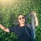 Carefree young happy smiling girl with braided hair lying in clover meadow or green grass, top view