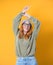 Carefree young woman with raised arms up, isolated on yellow background. Careless female person