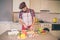 Careful cook stands and cut cucumber into pieces. He does it with knife. Guy looks down. He is serious and concentrated.