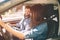 Careful driving. Beautiful young couple sitting on the front passenger seats and smiling while woman driving a car