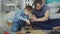 Careful father is teaching his son to work with electric screwdriver while son is trying to use gun and fix