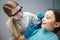 Careful female dentist hold tools close to girl mouth. Child show front teeth. She sit calmly in dental chair.