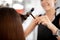 Careful hairdresser holding curling iron while working with client